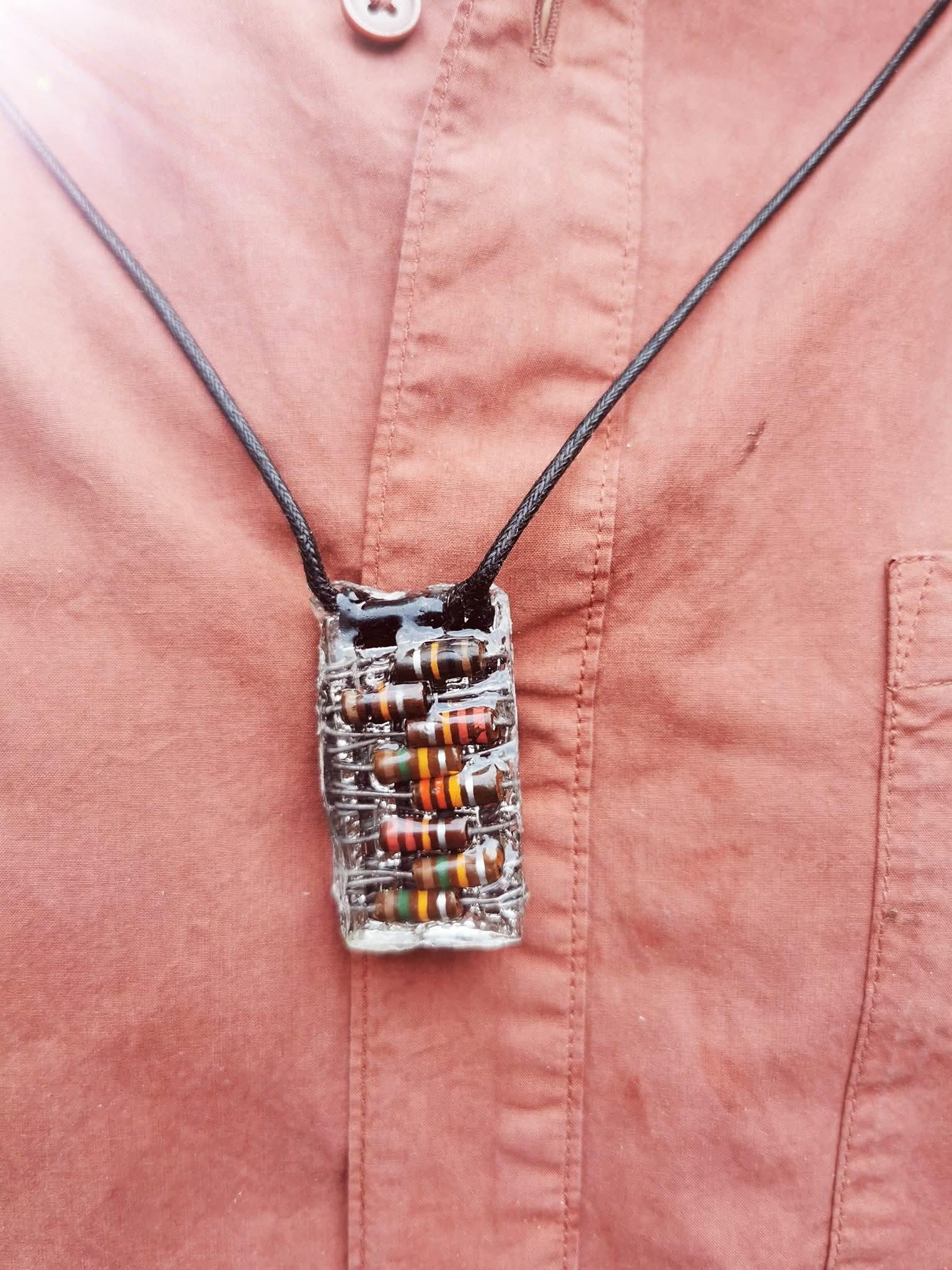 Gedragen ketting met rechthoekige hanger vol weerstanden, aan zwart koord